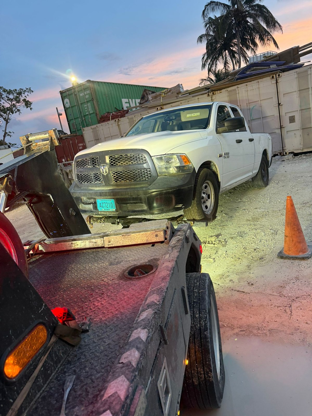 Gino's Towing flatbed loaded with a pickup truck at sunset in Nassau